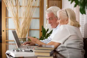 Senior couple working on laptop at home