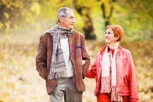 An elderly couple holding hands while walking in the park on a sunny day