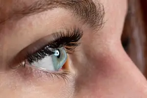 Close-up of a woman's eye with long eyelashes and a blue iris