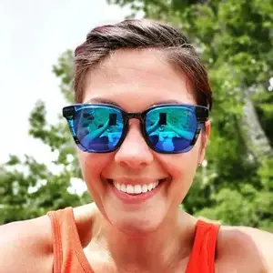 Woman smiling and taking a selfie with sunglasses reflecting her face