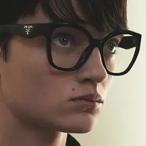 A close up of a person wearing Prada glasses looking to the left
