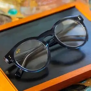 A pair of black-framed glasses with clear lenses on a wooden tray
