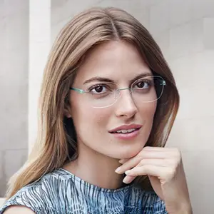 A woman with long blonde hair wearing clear-framed glasses is posing for a photo with a slight smile and one hand on her chin.