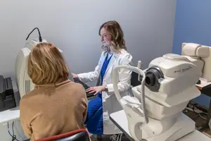 A woman doctor is performing an eye exam on a patient in an eye clinic.