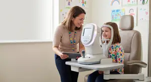 woman with tablet and young girl with eye exam machine