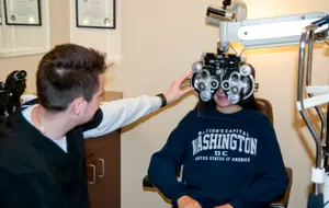 A person is adjusting an eye examination device on a patient's face.