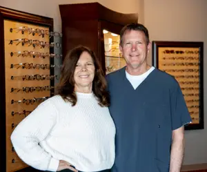 A man and woman standing in front of a display of glasses in an office