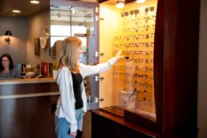 A woman looks at glasses on display in a store.