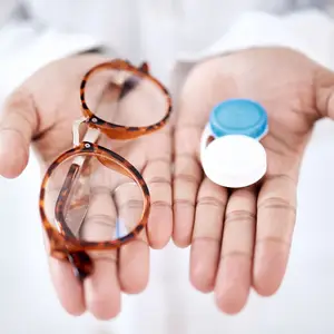 A pair of glasses with a blue and white contact lens case in a person's hand