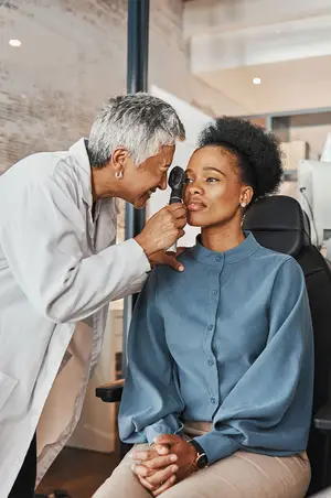 A doctor examining a patient's ear with an otoscope