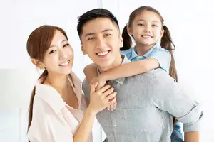 A family of three, a man, woman, and a little girl. The man is carrying the little girl on his back