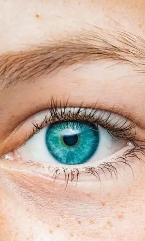 Close-up of a person's eye with turquoise iris and black pupil, eyelashes visible, skin freckles noticeable