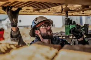 A man working on a ceiling with a power drill in his hand