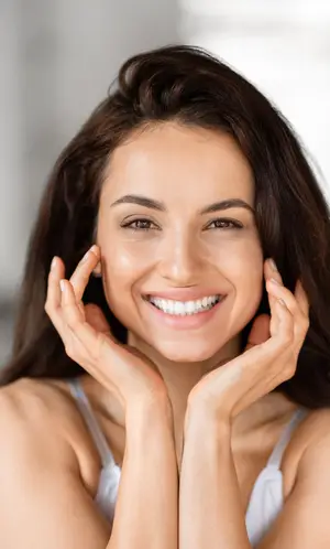 A smiling woman with her hands on her cheeks looking at the camera