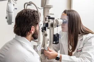 Optometrist checking a man's eyes with a slit lamp.