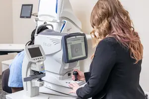 Woman examining a patient's eye using an eye examination machine