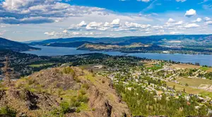 Aerial view of a city and a lake with mountains in the distance under a cloudy sky