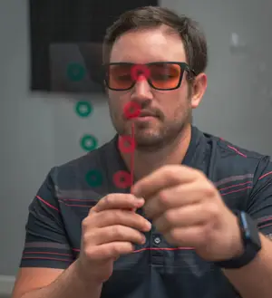 A man wearing sunglasses is looking at something with his hand on his chin.