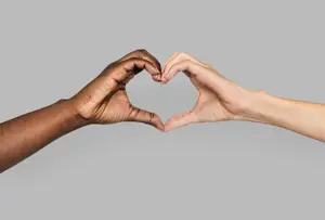Two hands forming a heart shape against a gray background