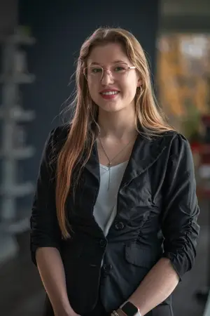 A woman with glasses and a black jacket posing for a picture