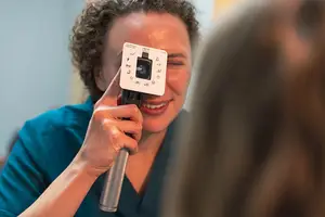 A person is holding a device with icons in front of another person's face.