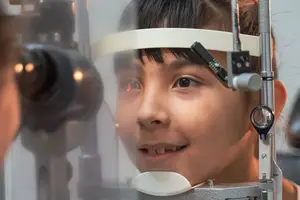 A young girl having her eyes checked by an optometrist using a phoropter