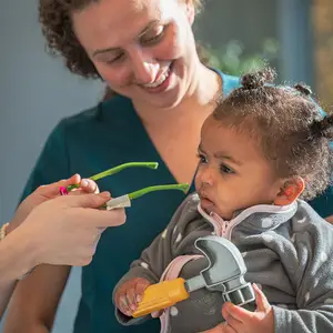 A woman holding a baby wearing glasses while another woman holds a pair of glasses