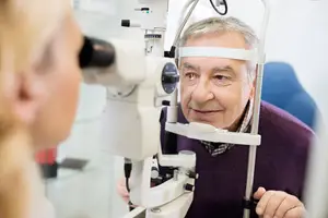 An elderly man is having his eyes examined by an optometrist in a clinic.