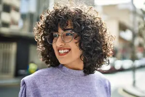portrait of woman smiling with curly hair and wearing glasses