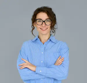 A woman wearing a blue striped shirt with glasses on is smiling and posing for the camera