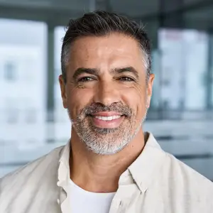 Smiling man with gray hair and beard standing in an office building