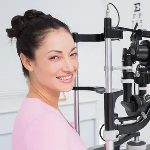 woman smiling while undergoing an eye exam