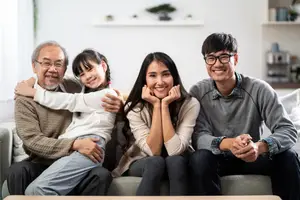 Three adults and a young girl smile and pose for a photo on a couch.