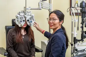 An eye doctor adjusts the device on a patient's head.
