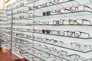 A wall of shelves displaying a variety of eyeglasses with different frames and lens colors