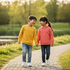 A boy and a girl in matching clothes are holding hands and smiling while walking down a brick path.