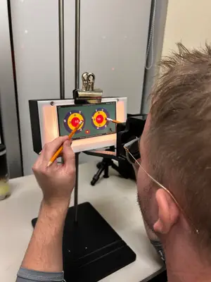 A man wearing glasses is drawing on a digital drawing board with a target on it