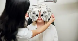A woman is having her eye examined by an optometrist using an ophthalmoscope.