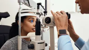 A female patient is having her eyes examined by a male optometrist in a clinic