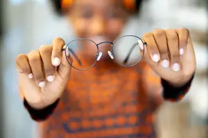 Close-up of a woman holding a pair of glasses.