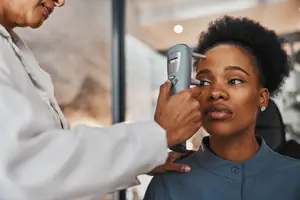 A woman is having her eyes examined by a doctor using a medical device
