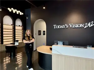 An employee of Today's Vision 242 stands in front of a reception desk in the office.