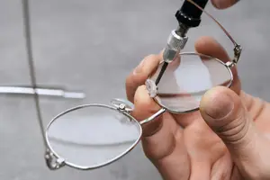 A person is adjusting a pair of eyeglasses using a tool, focusing on the detailed craftsmanship and the precision of the lenses.
