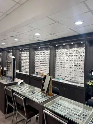 An interior of an optical shop with many glasses on display in cabinets and on tables.