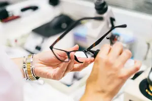 A woman is adjusting a pair of glasses in a laboratory.