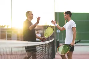 Two men are shaking hands on a tennis court