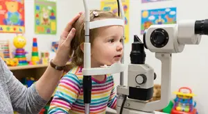 A little girl is getting her eyes examined at an optometrist's office.