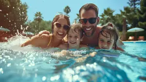 A family of four is swimming in a pool with a man and two girls smiling and posing for a photo