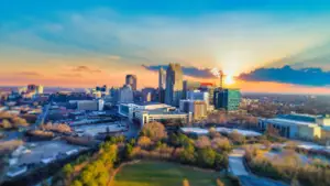 Aerial view of a city skyline with buildings and trees at sunset
