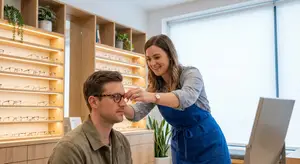 An optometrist is adjusting a patient's glasses in an optometrist's office